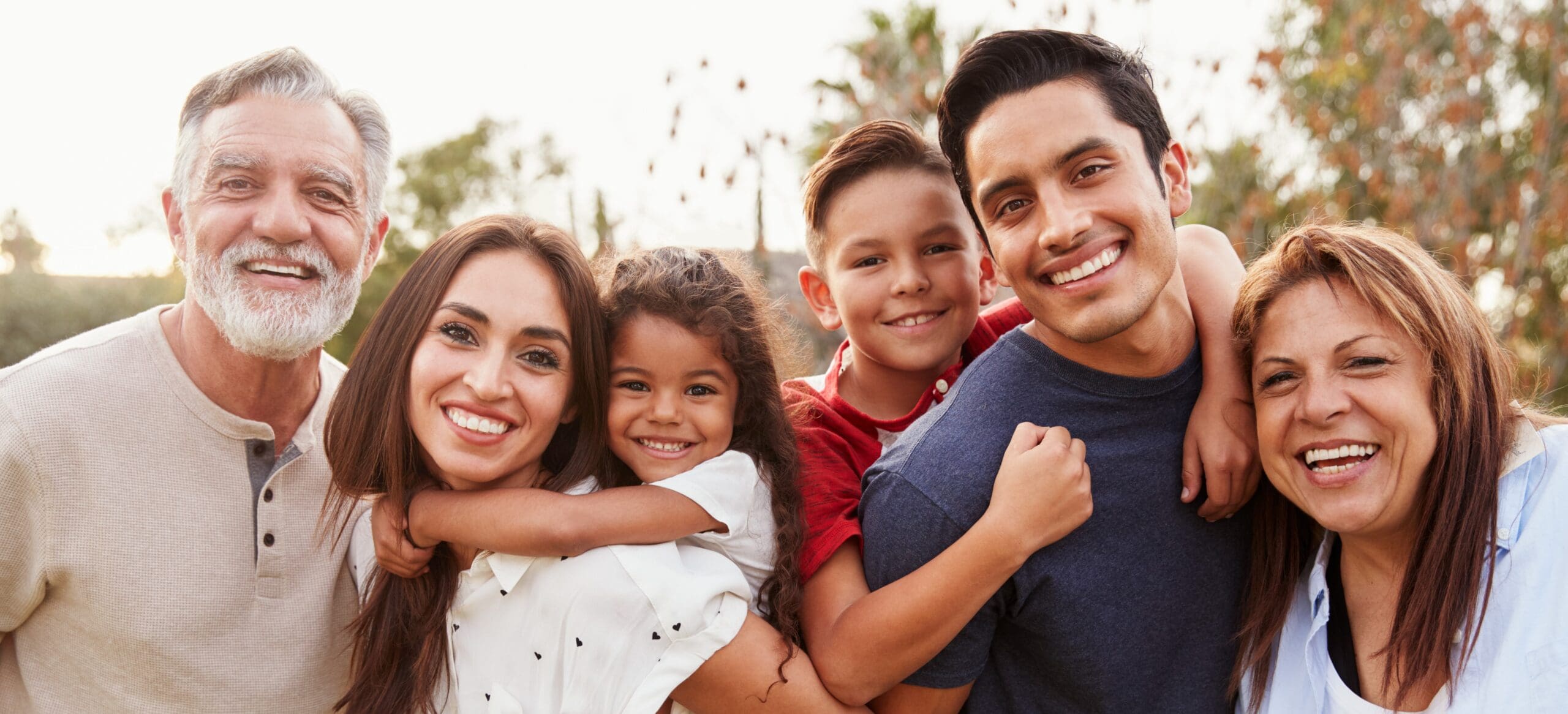 Three,generation,hispanic,family,standing,in,the,park,,smiling,to